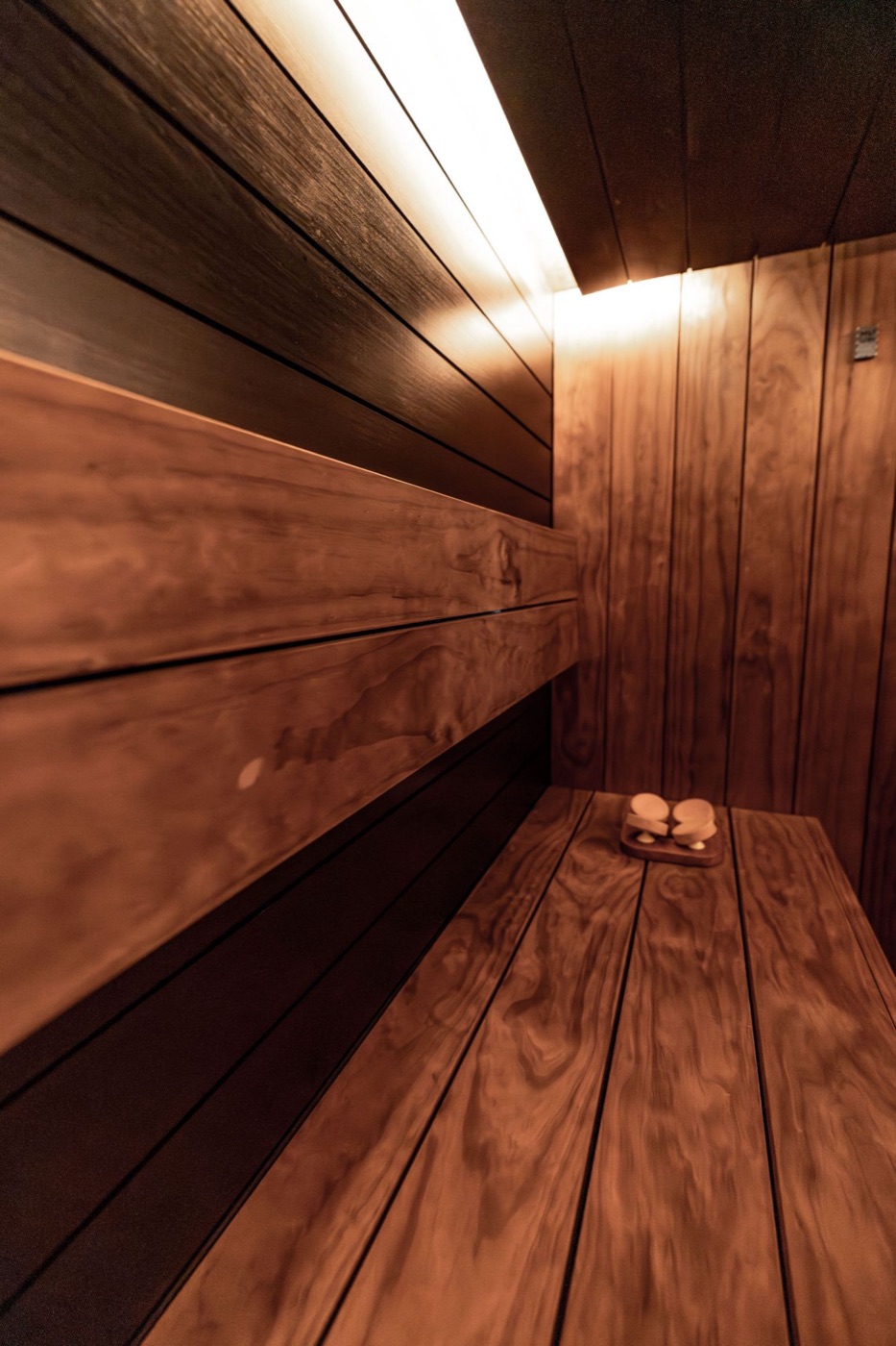 The inside of a wood-paneled infrared sauna with a lit bench