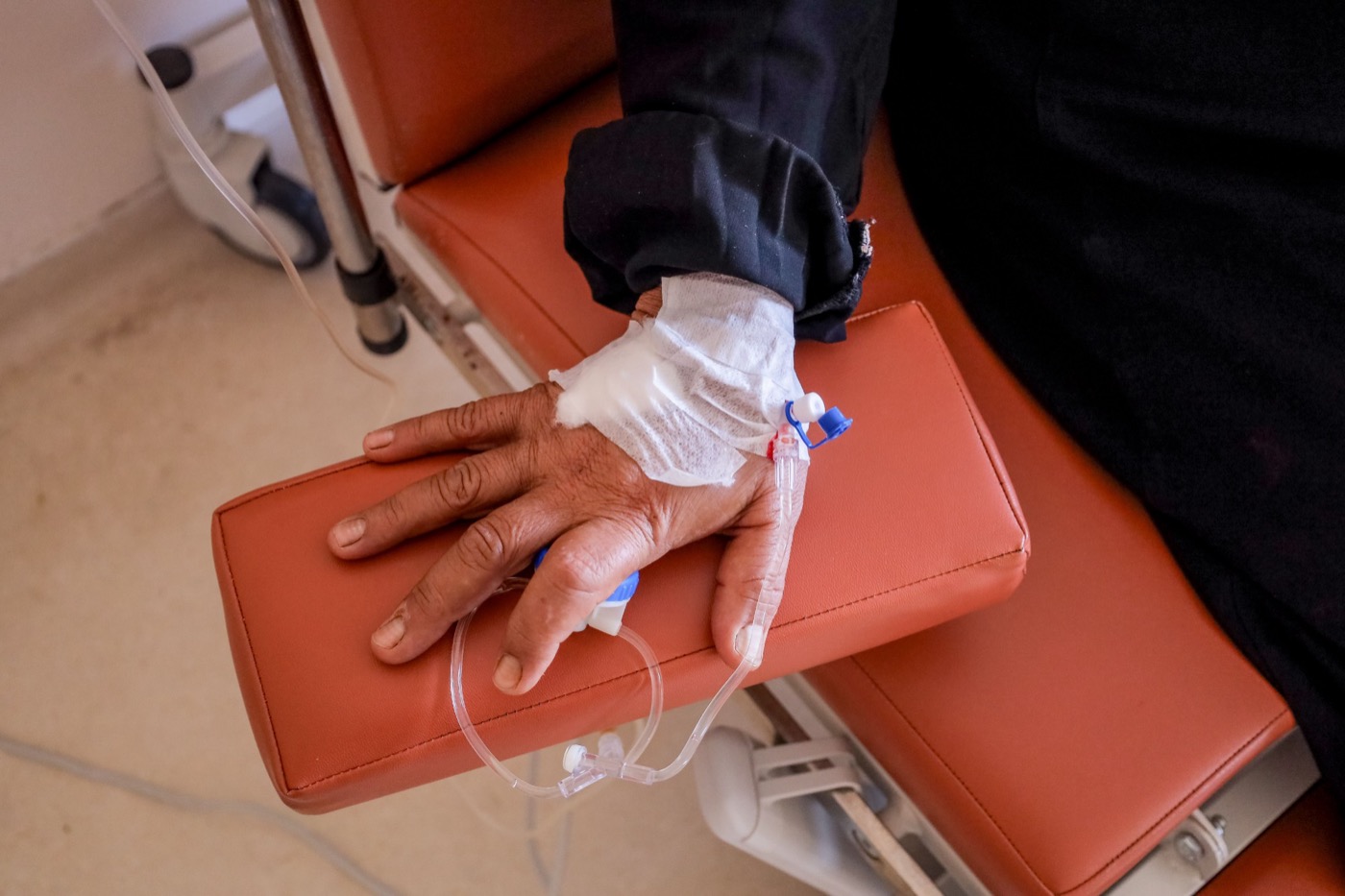 A close-up of an IV line placed and taped in a client's hand