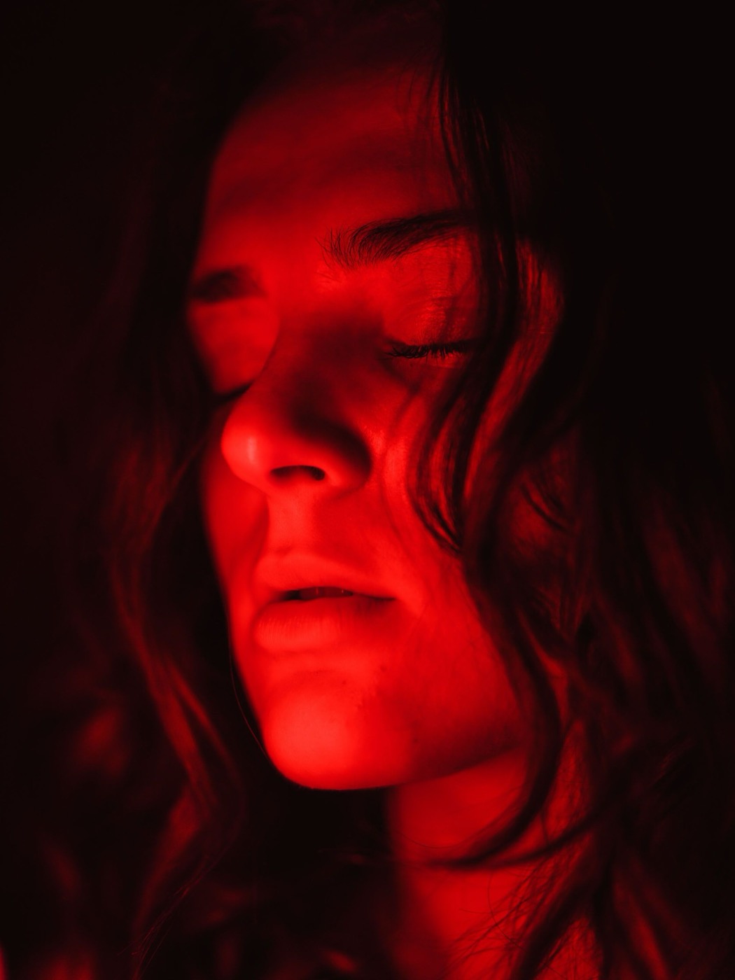 A client's face lit by a red light therapy panel